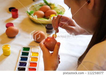 Happy pretty child girl having fun during painting eggs for Easter in spring time at home. Child painting eggs. Happy family preparing for Easter while enjoying DIY decorating at home. Copy space. Happy pretty child girl having fun during painting eggs for Easter in spring time at home. Child painting eggs. Happy family preparing for Easter while enjoying DIY decorating at home. Copy space. 112258077