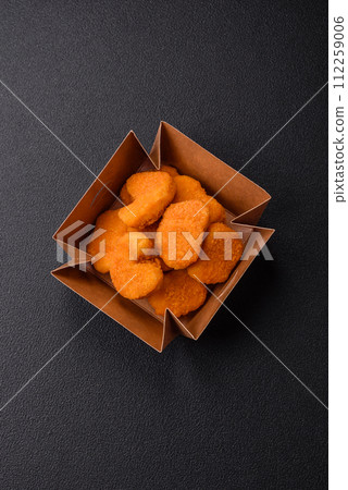 Delicious fresh crispy chicken nuggets on a dark concrete background 112259006