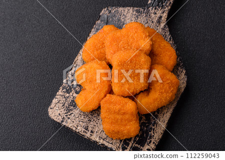 Delicious fresh crispy chicken nuggets on a dark concrete background 112259043