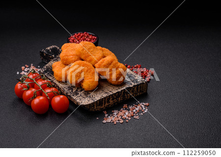 Delicious fresh crispy chicken nuggets on a dark concrete background Delicious fresh crispy chicken nuggets on a dark concrete background 112259050