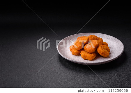 Delicious fresh crispy chicken nuggets on a dark concrete background Delicious fresh crispy chicken nuggets on a dark concrete background 112259066