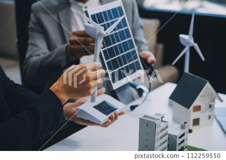 Two Young Engineers Expertise in Solar Cell Installation Meetings and Discussion in The Job. Planning to Install Solar Photovoltaic Panels on Roof Top in The Office Room with Factory Building Plan. 112259550