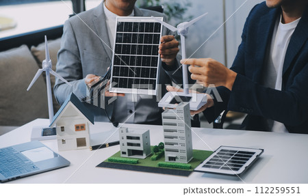 Two Young Engineers Expertise in Solar Cell Installation Meetings and Discussion in The Job. Planning to Install Solar Photovoltaic Panels on Roof Top in The Office Room with Factory Building Plan. Two Young Engineers Expertise in Solar Cell Installation Meetings and Discussion in The Job. Planning to Install Solar Photovoltaic Panels on Roof Top in The Office Room with Factory Building Plan. 112259551