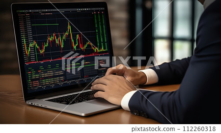 A businessman in a suit is using a laptop to track stock prices. 112260318