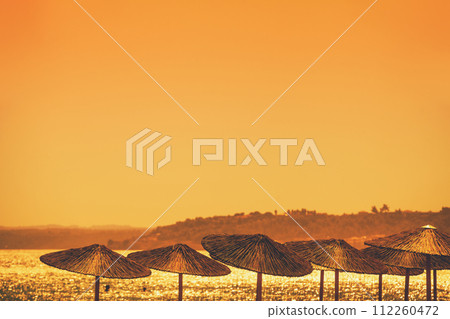 Seascape with straw sun umbrellas on the beach 112260472