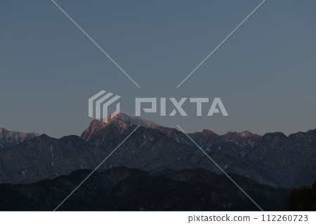 Mt. Kaikomagatake in the Southern Alps in the harsh winter illuminated by Asai 112260723