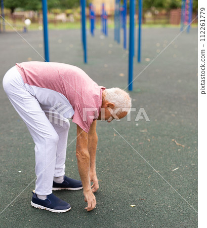 Grandfather jogger doing stretching outdoors before running in summer park 112261779