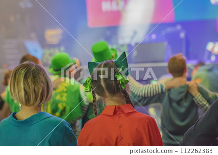 Rear view of two young women in green outfits and decorations at Saint Patrick's Day party celebration 112262383