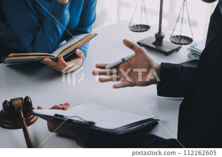 Justice and Law concept. Legal counsel presents to the client a signed contract with gavel and legal law or legal having team meeting at law firm in background 112262605