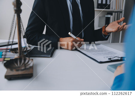 Justice and Law concept. Legal counsel presents to the client a signed contract with gavel and legal law or legal having team meeting at law firm in background 112262617