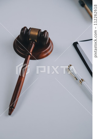 Justice and Law concept. Legal counsel presents to the client a signed contract with gavel and legal law or legal having team meeting at law firm in background 112262618