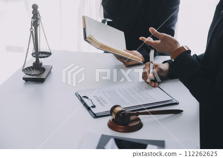 Justice and Law concept. Legal counsel presents to the client a signed contract with gavel and legal law or legal having team meeting at law firm in background Justice and Law concept. Legal counsel presents to the client a signed contract with gavel and legal law or legal having team meeting at law firm in background 112262625