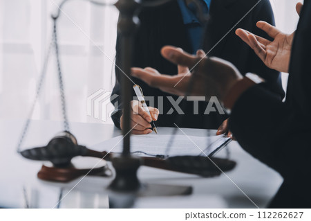 Justice and Law concept. Legal counsel presents to the client a signed contract with gavel and legal law or legal having team meeting at law firm in background Justice and Law concept. Legal counsel presents to the client a signed contract with gavel and legal law or legal having team meeting at law firm in background 112262627
