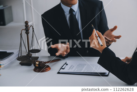 Justice and Law concept. Legal counsel presents to the client a signed contract with gavel and legal law or legal having team meeting at law firm in background 112262628