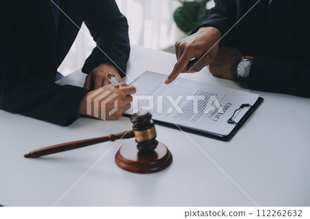 Justice and Law concept. Legal counsel presents to the client a signed contract with gavel and legal law or legal having team meeting at law firm in background 112262632