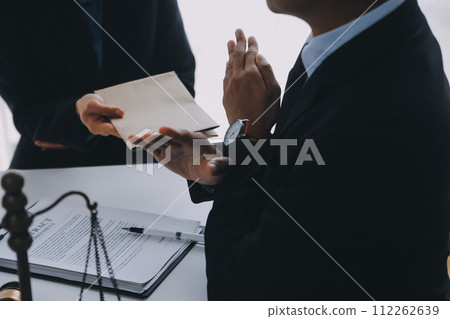 Justice and Law concept. Legal counsel presents to the client a signed contract with gavel and legal law or legal having team meeting at law firm in background 112262639