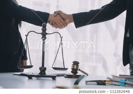 Justice and Law concept. Legal counsel presents to the client a signed contract with gavel and legal law or legal having team meeting at law firm in background Justice and Law concept. Legal counsel presents to the client a signed contract with gavel and legal law or legal having team meeting at law firm in background 112262646