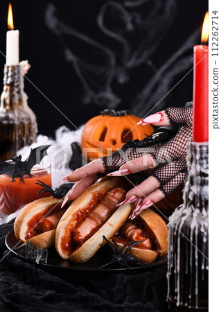 Bloody hot dog in the hands of a witch 112262714