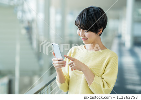 一名年輕女子正在操作智慧型手機。 112262758