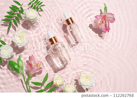 Cosmetic bottles with pipette and flowers. 112262768