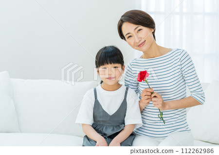 A mother receives a carnation from her daughter on Mother's Day. 112262986