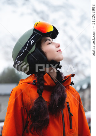young woman of Caucasian ethnicity looks to the side and smiles, raising her head to the sky, enjoying her vacation at the ski resort 112262998