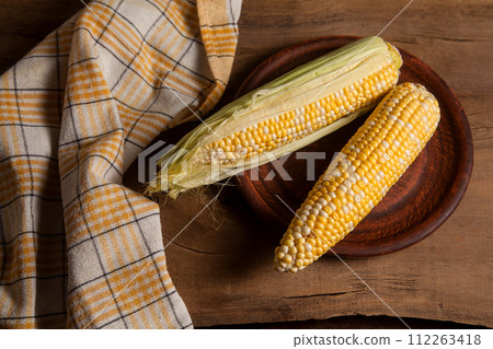 Clay plate with two cobs sweet corn on wooden background.. Clay plate with two cobs sweet corn on wooden background.. 112263418