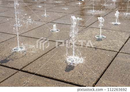 Water droplets spread from the fountain in the air. Splashing water from a fountain in the park Water droplets spread from the fountain in the air. Splashing water from a fountain in the park 112263692