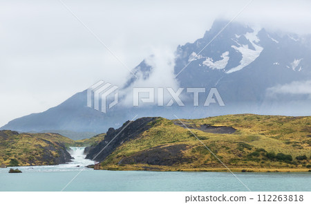 Tranquil Landscape with Waterfall and Misty Mountain Peaks 112263818