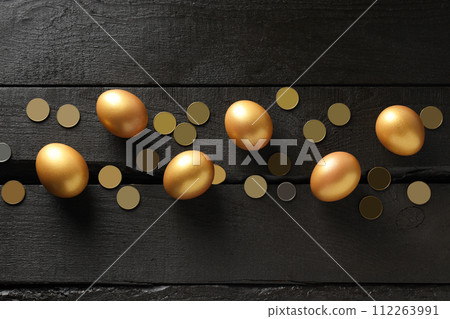 Golden eggs with coins on a dark background Golden eggs with coins on a dark background 112263991