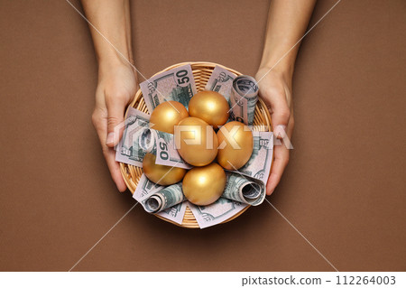 Golden eggs with money on a brown background Golden eggs with money on a brown background 112264003
