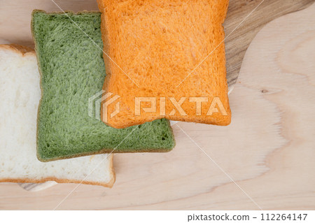 Three types of bread lined up on a cutting board: Carrot and spinach vegetable bread Three types of bread lined up on a cutting board: Carrot and spinach vegetable bread 112264147