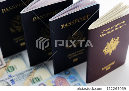 3 United States and 1 France passport on visable currency transparent background. High camera angle. Concept of business, trade, employment, vacation travel. Concept coming summer Olympics. Closeup 3 United States and 1 France passport on visable currency transparent background. High camera angle. Concept of business, trade, employment, vacation travel. Concept coming summer Olympics. Closeup 112265069