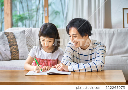 Young father teaching his daughter studies in the living room 112265075