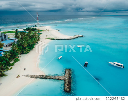 Maldives tropical beach with pier and boats in blue ocean. Travel vacation concept. Aerial view Maldives tropical beach with pier and boats in blue ocean. Travel vacation concept. Aerial view 112265482