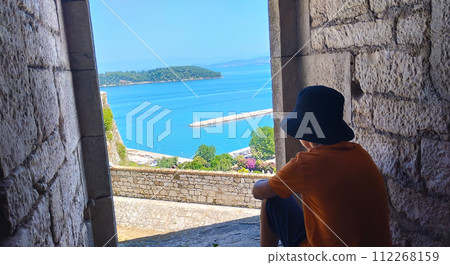 The boy looks out of the window of the fortress at the sea The boy looks out of the window of the fortress at the sea 112268159
