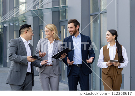Group of happy business professionals in a casual meeting outside an office. They are discussing work and sharing a laugh. 112268617