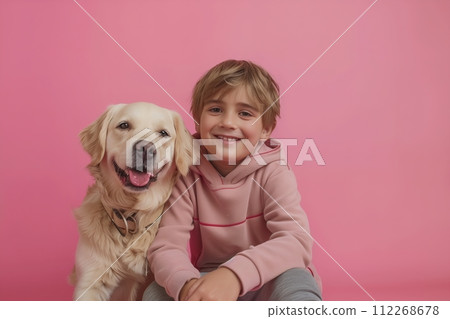A young boy is sitting on a pink background with a golden retriever 112268678