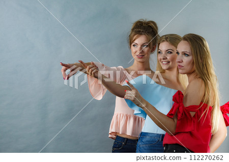Fashionable adult female friends models pointing at grey copy space. Fashionable adult female friends models pointing at grey copy space. 112270262
