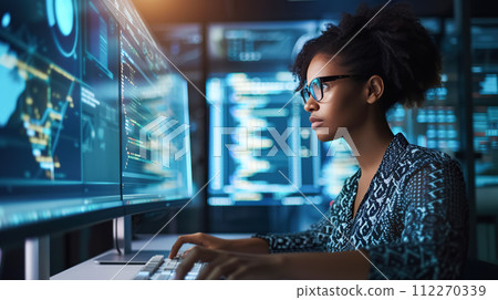AI-generated content. Focused dark-skinned female programmer working hard in a darkened office illuminated by the light of computer screens, representing dedication to the high tech industry 112270339