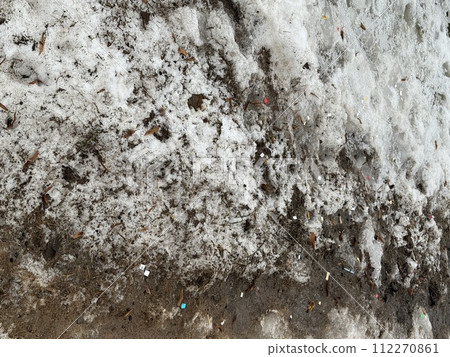 Melting dirty snow on the streets of the city during the daytime in winter. Snow with sand and mud lies on the road Melting dirty snow on the streets of the city during the daytime in winter. Snow with sand and mud lies on the road 112270861