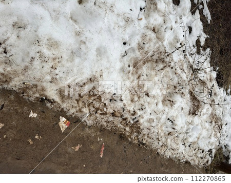 Melting dirty snow on the streets of the city during the daytime in winter. Snow with sand and mud lies on the road Melting dirty snow on the streets of the city during the daytime in winter. Snow with sand and mud lies on the road 112270865