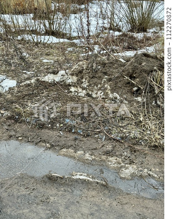Melting dirty snow on the streets of the city during the daytime in winter. Snow with sand and mud lies on the road Melting dirty snow on the streets of the city during the daytime in winter. Snow with sand and mud lies on the road 112270872