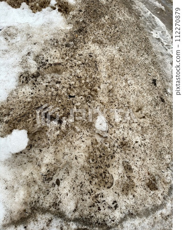 Melting dirty snow on the streets of the city during the daytime in winter. Snow with sand and mud lies on the road Melting dirty snow on the streets of the city during the daytime in winter. Snow with sand and mud lies on the road 112270879