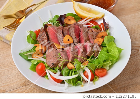 A hearty steak salad, vegetable salad, beef thigh steak, and dressing. 112271193