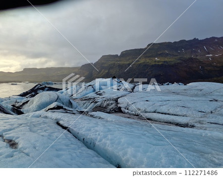 Massive ice blocks forming glacier lagoon with nordic landscape, vatnajokull glacier cap creating wintry icelandic scenery. Icebergs chunks cracking inside frozen lake in iceland, glacier hiking. Massive ice blocks forming glacier lagoon with nordic landscape, vatnajokull glacier cap creating wintry icelandic scenery. Icebergs chunks cracking inside frozen lake in iceland, glacier hiking. 112271486