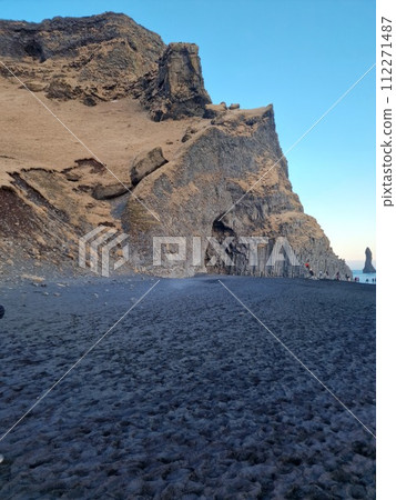 Huge basalt rocks on reynisfjara beach, icelandic rock formations stacked in blocks on reynisfjall mountain. Majestic unique nature creating beautiful scenery, black sand beach in iceland. Huge basalt rocks on reynisfjara beach, icelandic rock formations stacked in blocks on reynisfjall mountain. Majestic unique nature creating beautiful scenery, black sand beach in iceland. 112271487