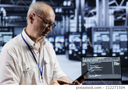 Aged precise engineer coding in technologically advanced data center using javascript language. Expert updating software on server racks on laptop terminal, ensuring errorless performance and security Aged precise engineer coding in technologically advanced data center using javascript language. Expert updating software on server racks on laptop terminal, ensuring errorless performance and security 112271504