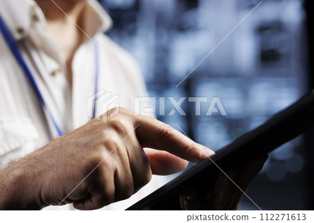 Qualified electrician inspects server rows in computer network security data center, ensuring optimal performance. Certified wireman monitoring energy consumption across infrastructure parts, close up 112271613