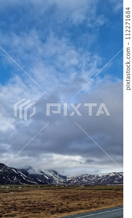 Majestic long road scenery in arctic countryside with fields and snowy hilltops, icelandic natural landscape. Fantastic highway lonely road concept in nordic setting, scenic route. Majestic long road scenery in arctic countryside with fields and snowy hilltops, icelandic natural landscape. Fantastic highway lonely road concept in nordic setting, scenic route. 112271684